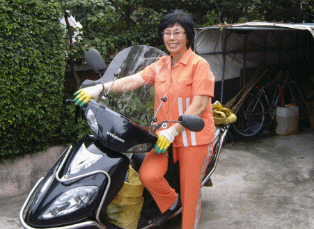 일터로 나갈때 자신이 타고 다니는 이륜차 앞에서 잠깐 포즈를 취하는 김금례씨